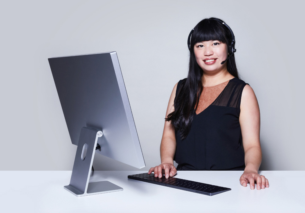 customer service agent wearing headset standing beside a computer monitor